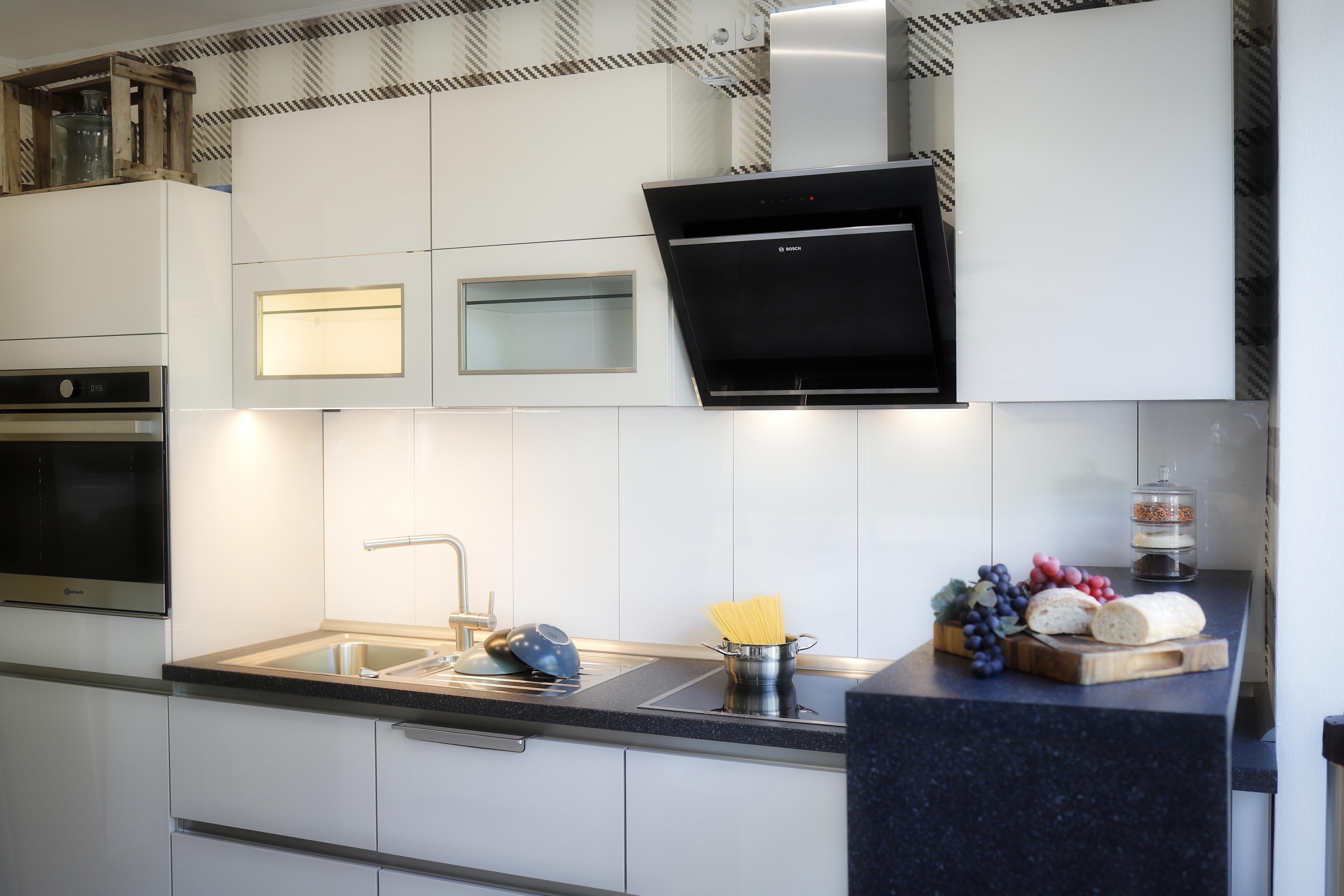 Weiße Ausstellungs-Küche mit dunkler Arbeitsplatte und Esche