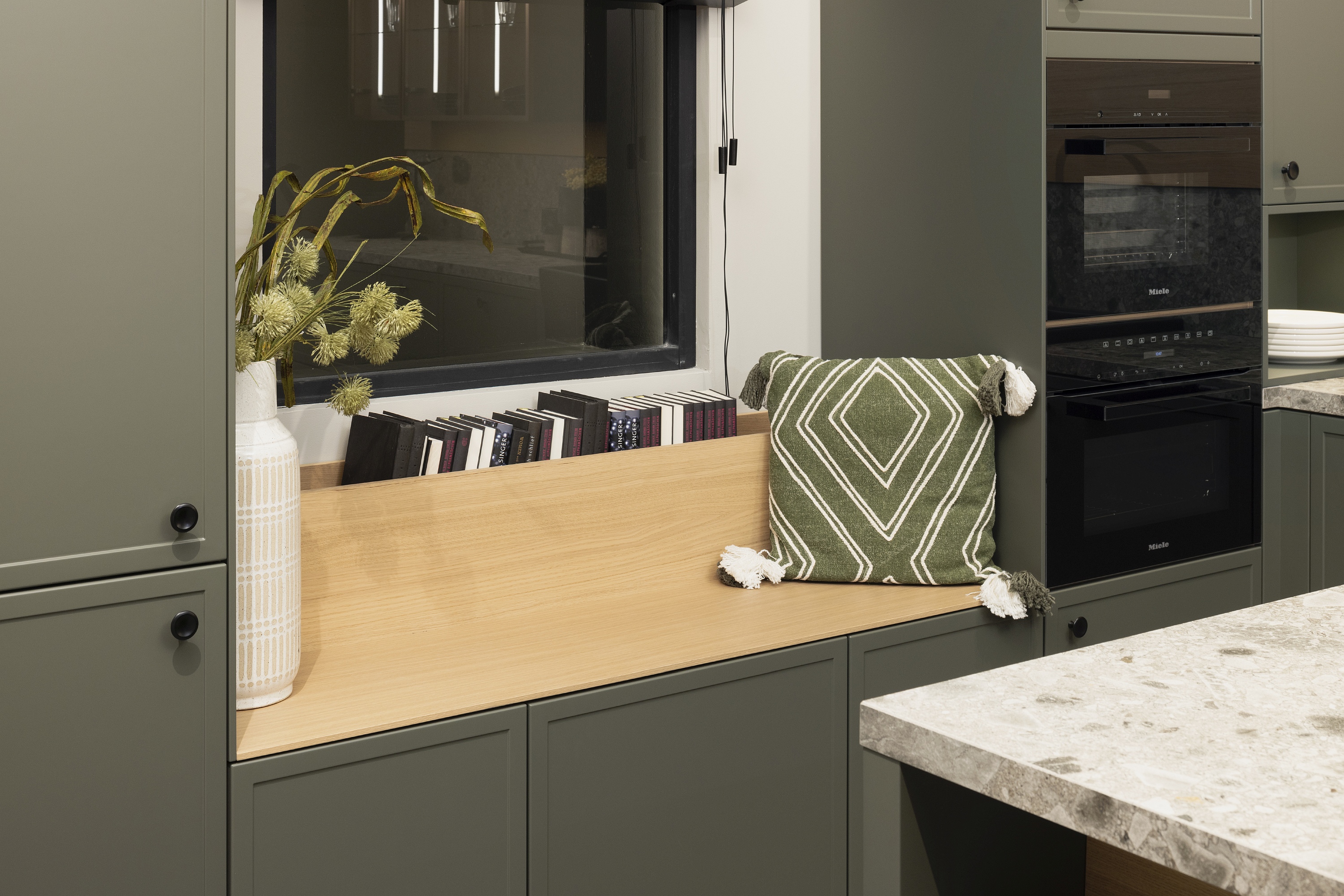 Sitznische aus hellem Holz in einer dunkelgrauen modernen Landhausküche von Häcker